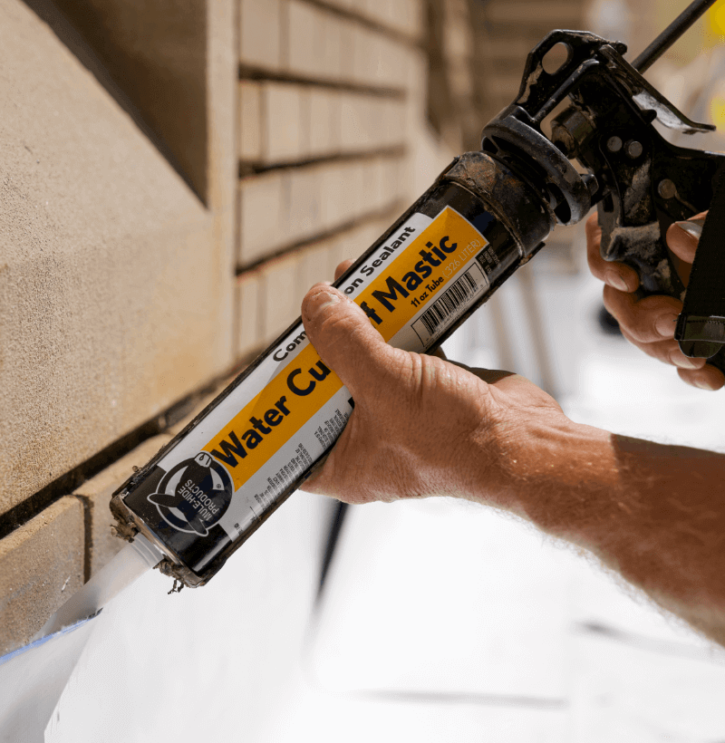 A roofer works with caulk.